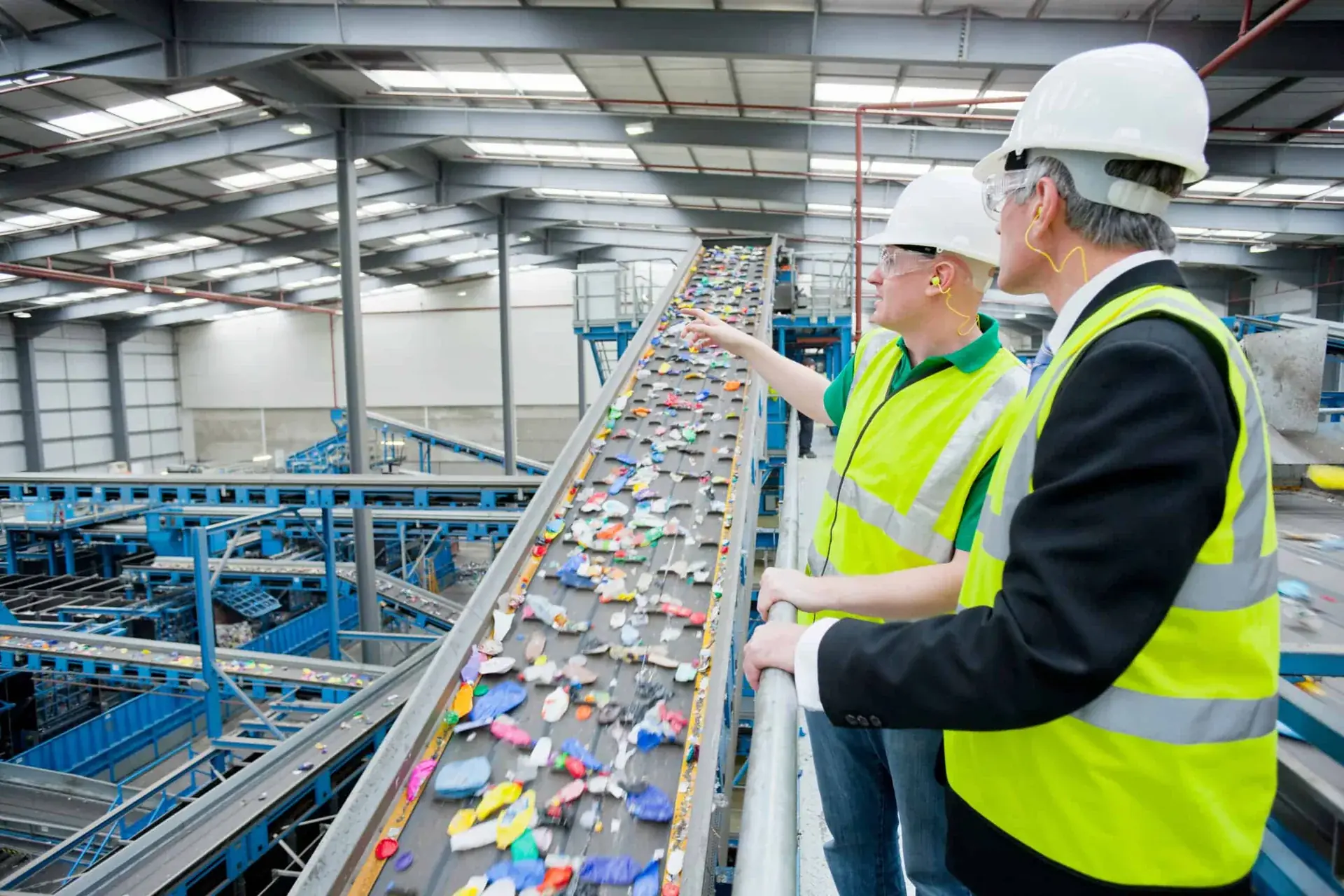 Workers inspecting mixed plastic on a recycling facility sorting line